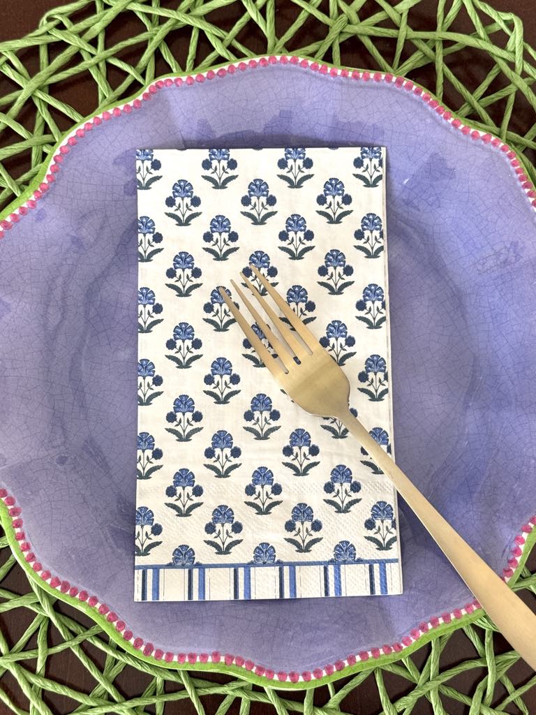 Block print paper guest towels on a lavender colored plate.
