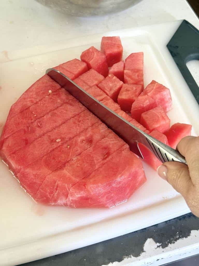 Cutting a watermelon into chunks with a knife.