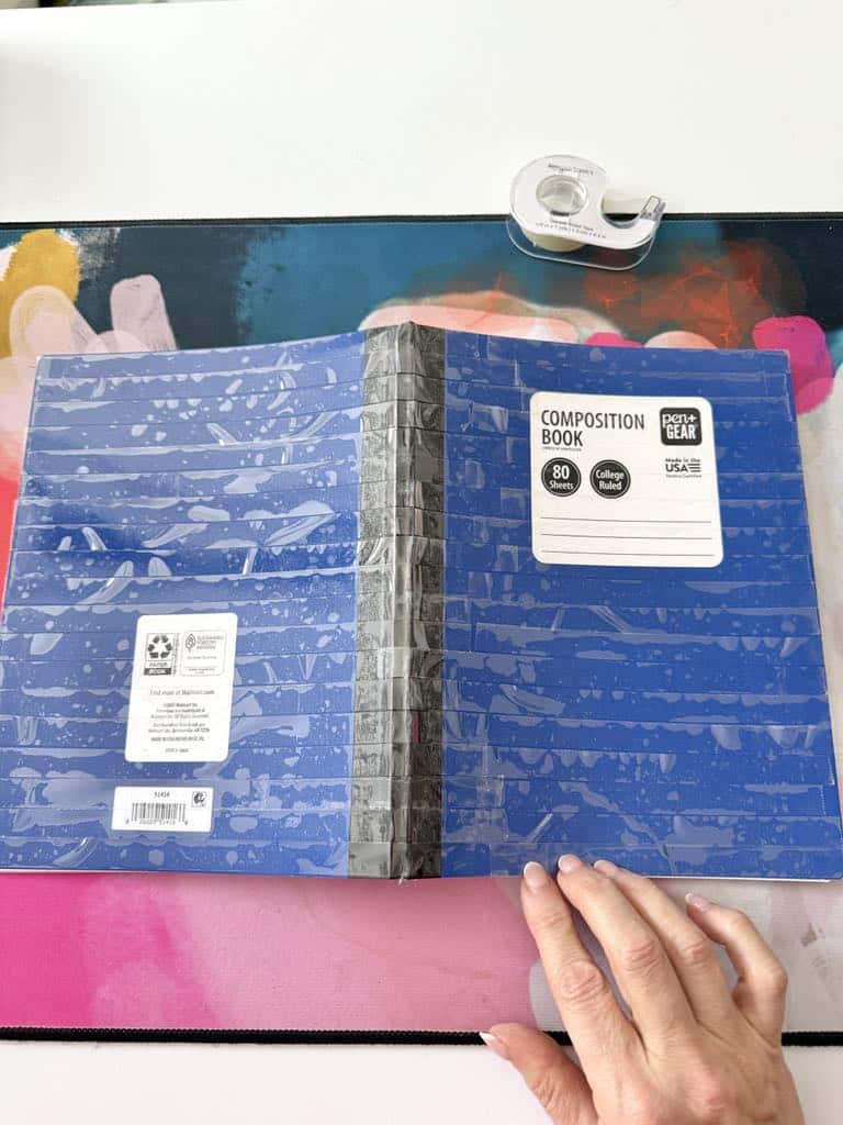 A composition notebook covered with double-sided tape.