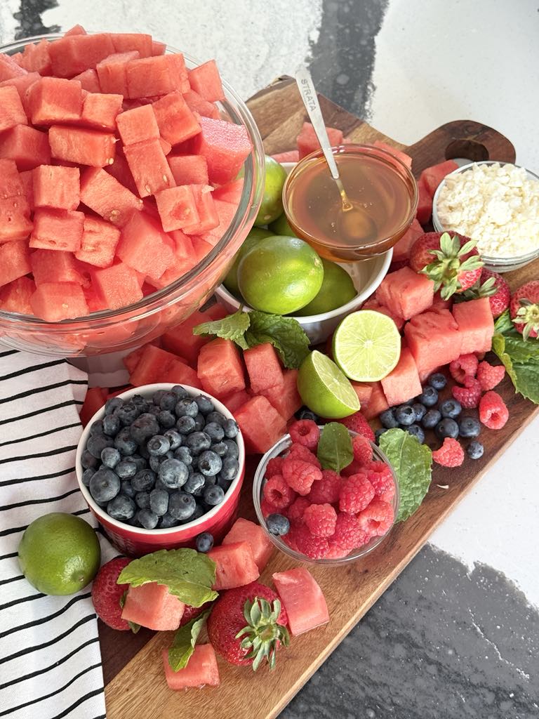 Watermelon, berries, honey, limes, and mint for a watermelon fruit salad.