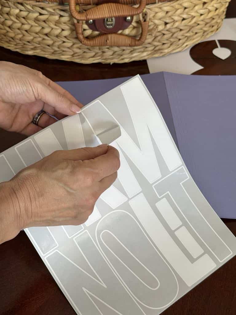 Peeling a "M" sticker from paper.