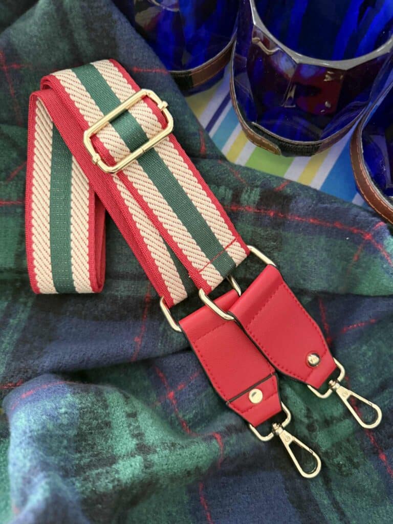 A red, green, and cream striped guitar strap purse handle.
