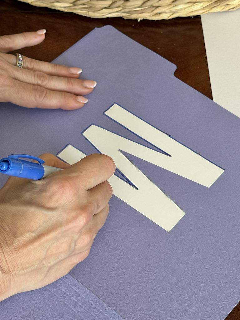 Tracing around an "M" sticker on a file folder.
