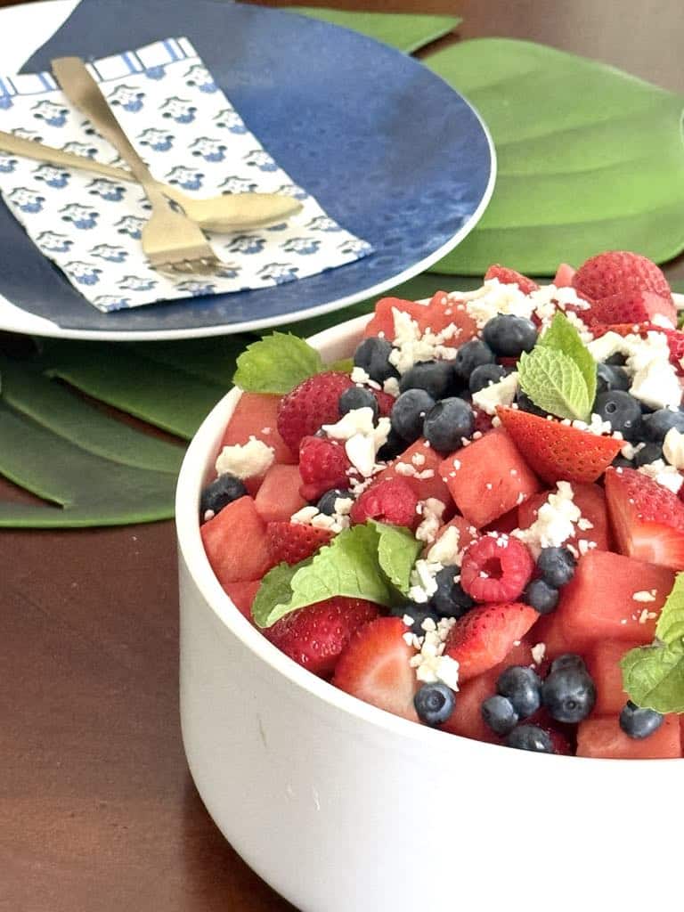 Table setting with a bowl of watermelon fruit salad with honey lime dressing.