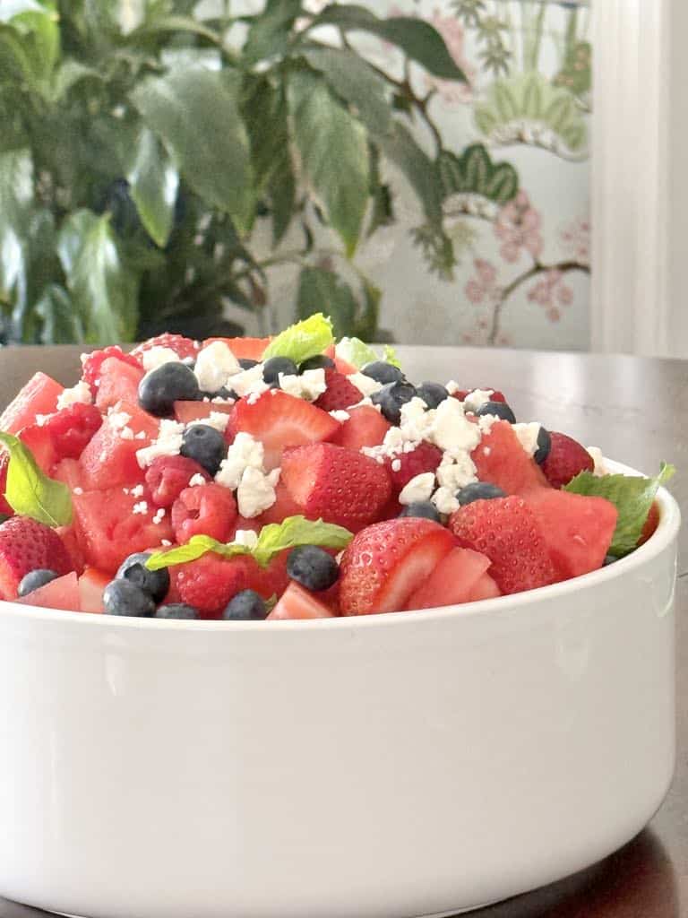Watermelon  and berry fruit salad in a large white bowl.