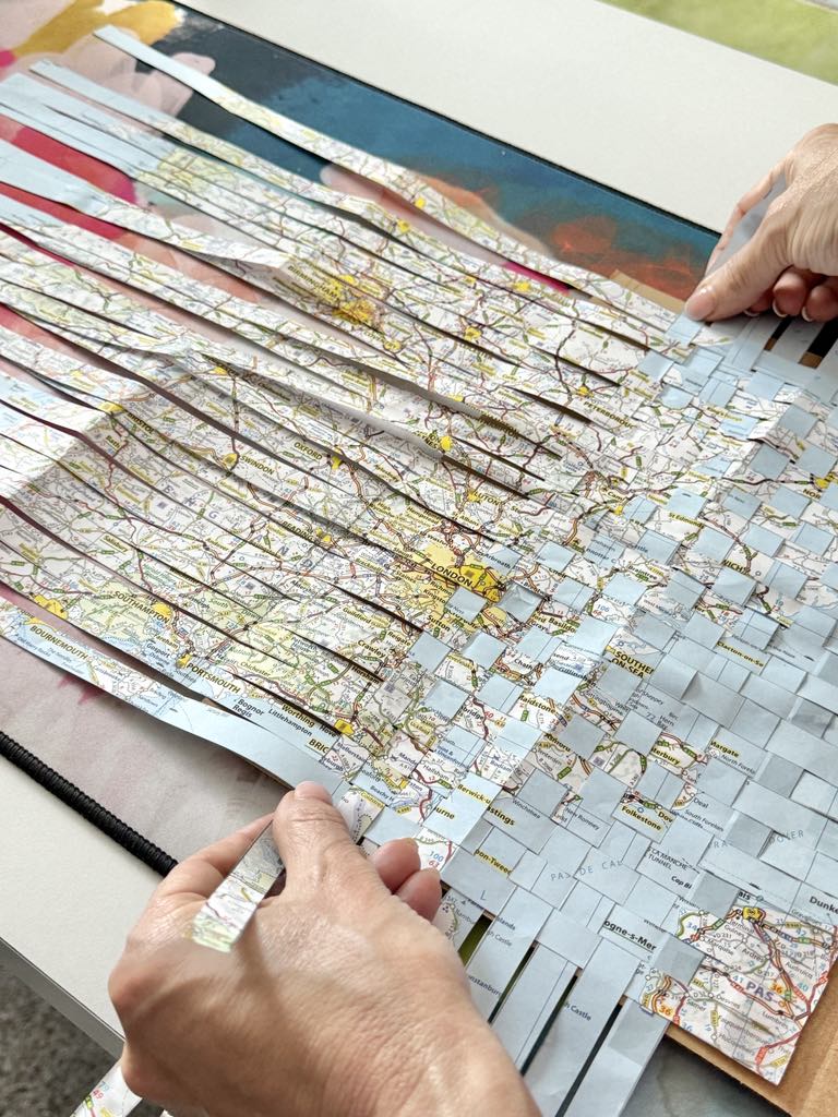 Weaving strips of a map together to create the cover of a travel journal.