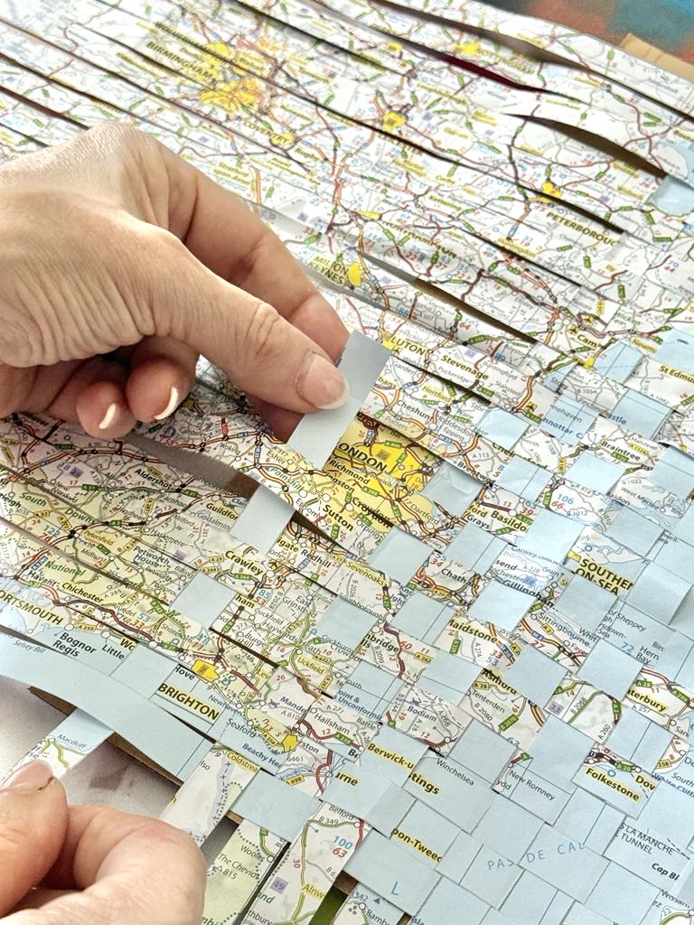 Weaving paper map strips for travel journal cover.