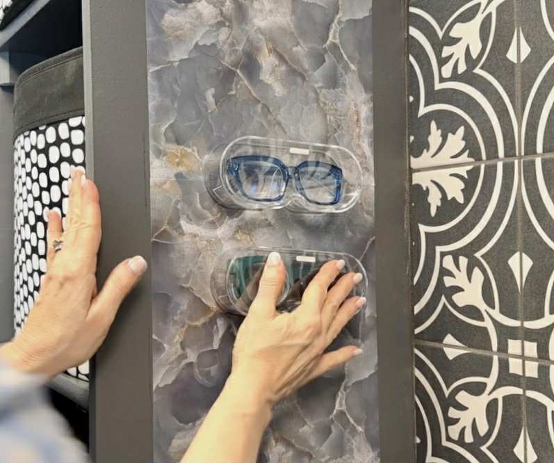Pressing acrylic eyewear storage cases onto a wall for how to organize sunglasses.