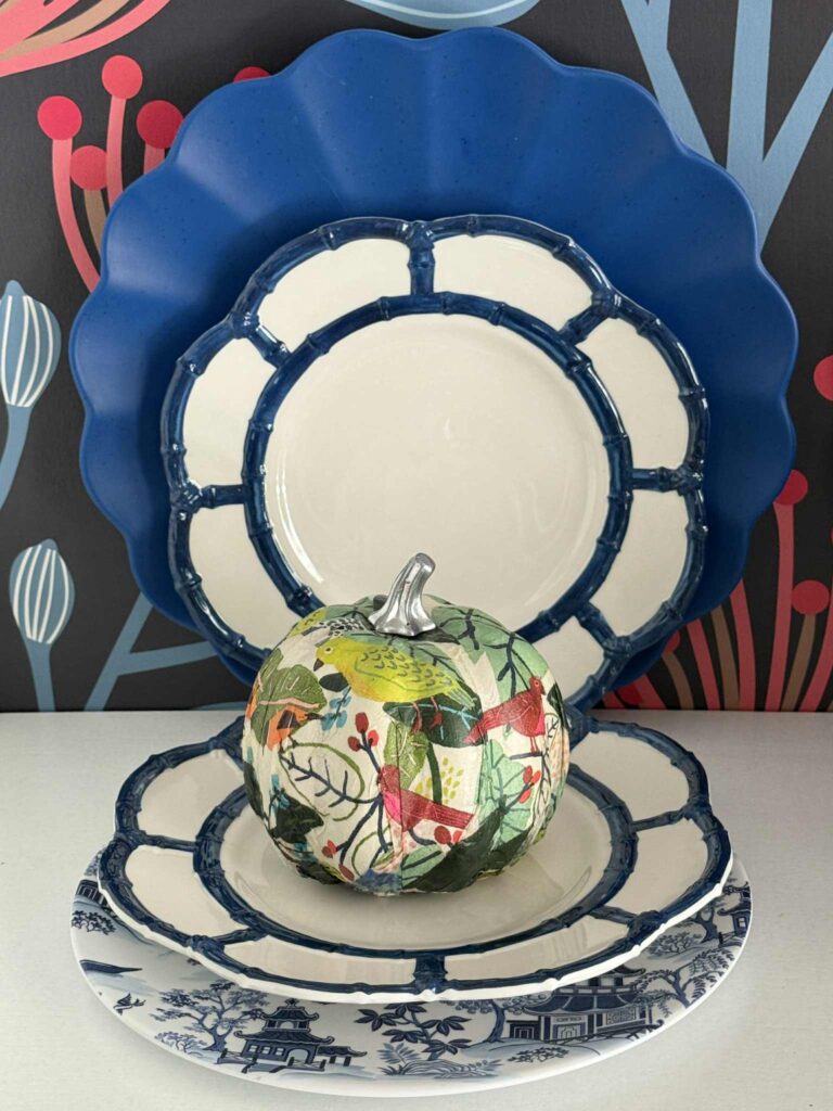 Layered blue and white plates with a colorful pumpkin sitting on top.