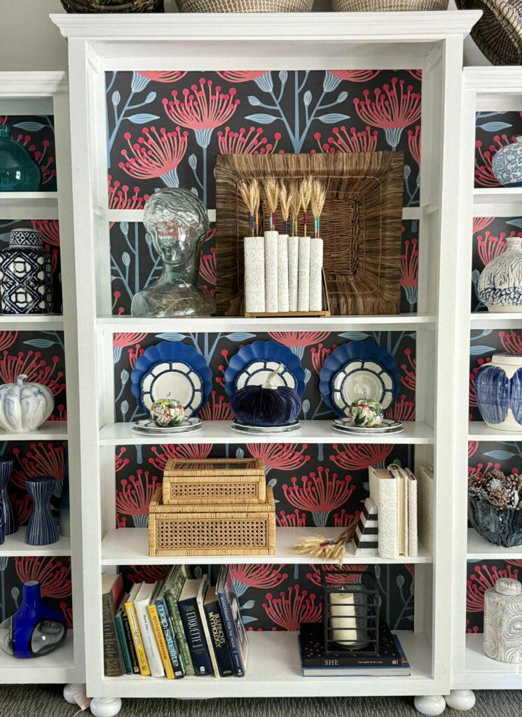 Bookshelves styled for fall with colorful plates, pumpkins, and DIY book covers.