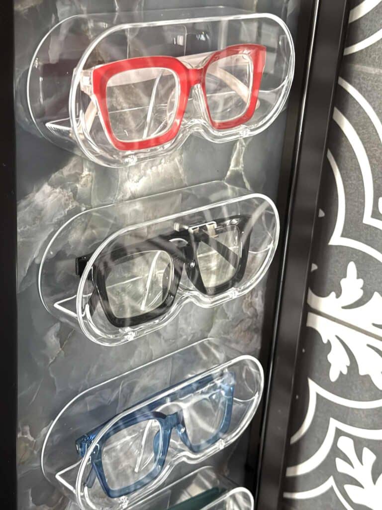 Red reading glasses in clear acrylic box hanging on a wall.