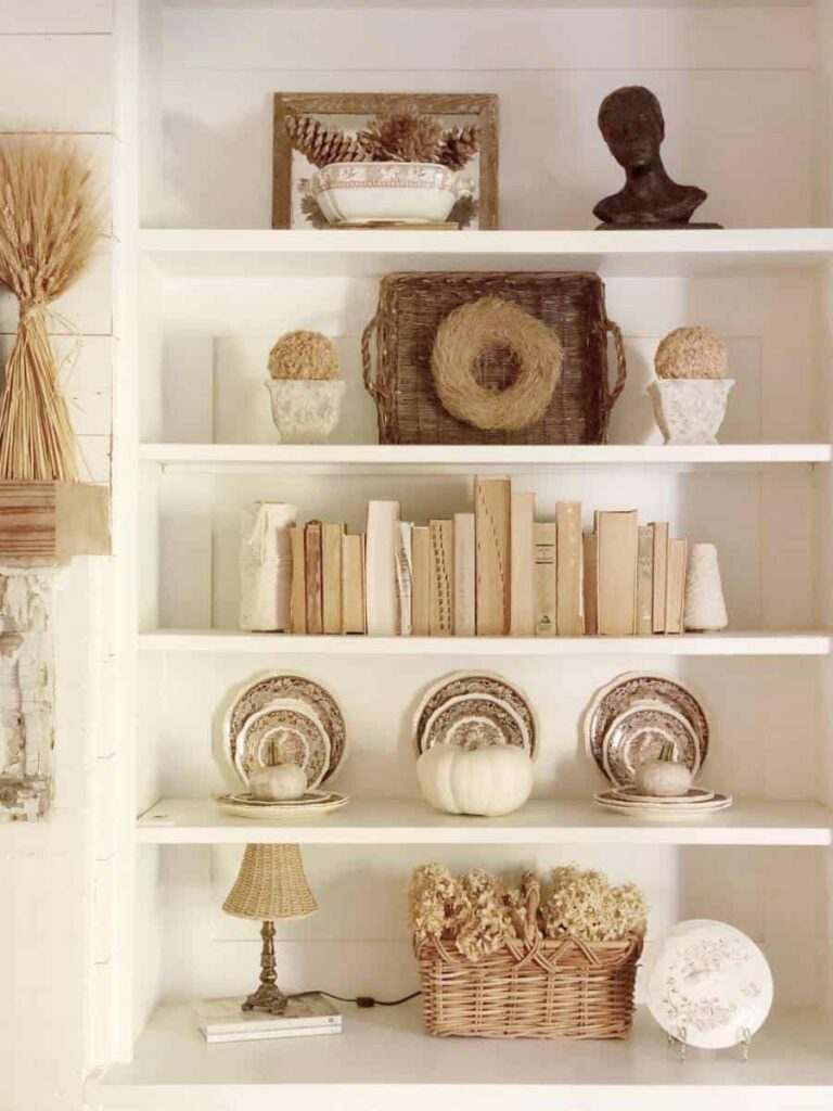 Bookshelves styled with neutral books, plates, and pumpkins.