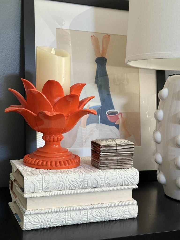 A pile of three books wrapped in diy wallpaper book covers sitting on a bedroom nightstand.