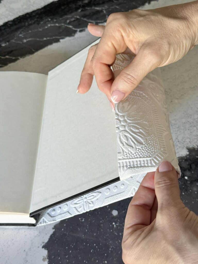 Wrapping a diy book cover made from wallpaper onto a book.