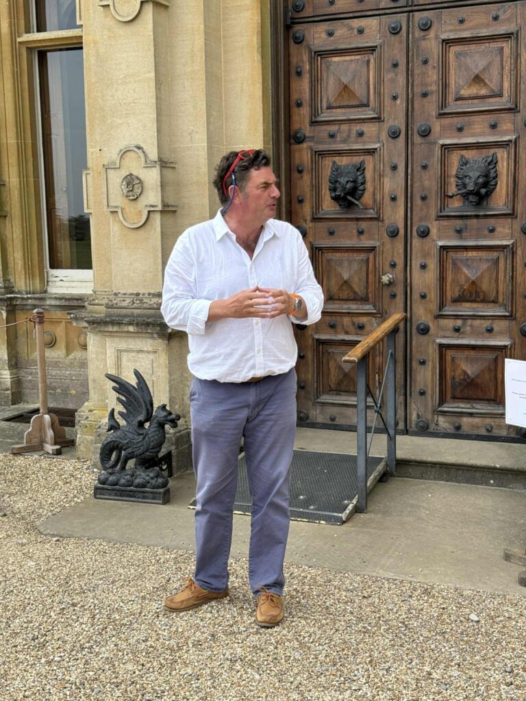 A man standing in front of Highclere castle front doors.