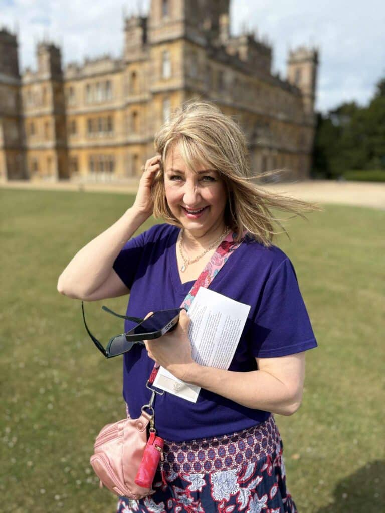 Woman standing on path in front of Highclere Caste: home of the Downton Abbey television series.