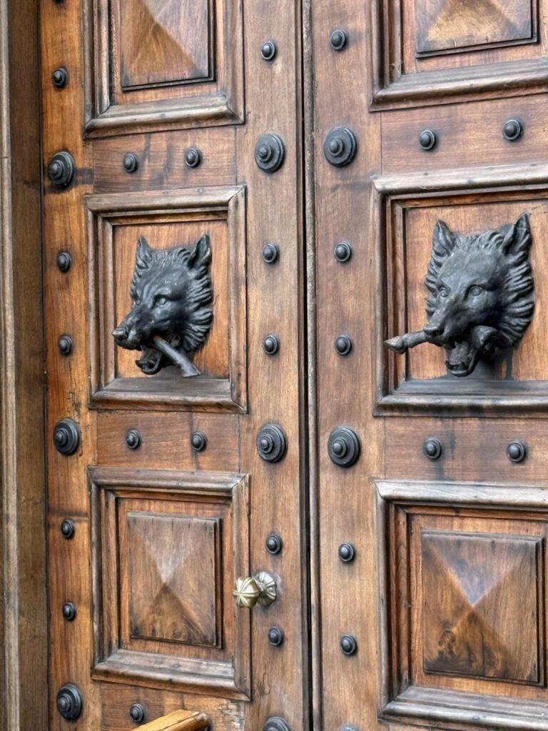Wooden doors with iron wolves mounted on the front.