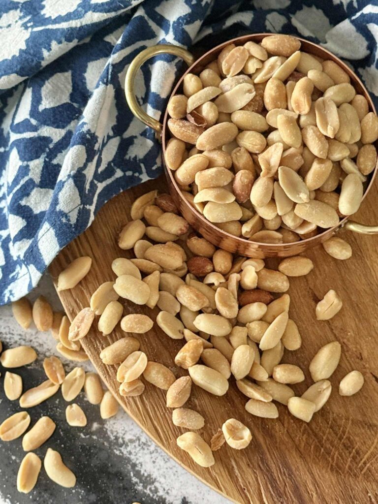 A measuring cup full of salted peanuts.