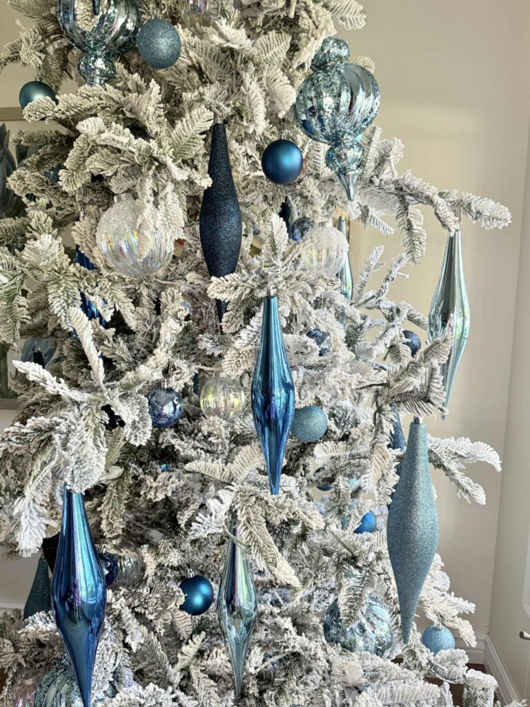 Decorating Ideas for a flocked Christmas tree: Spindle shaped ornaments hang from a flocked tree.