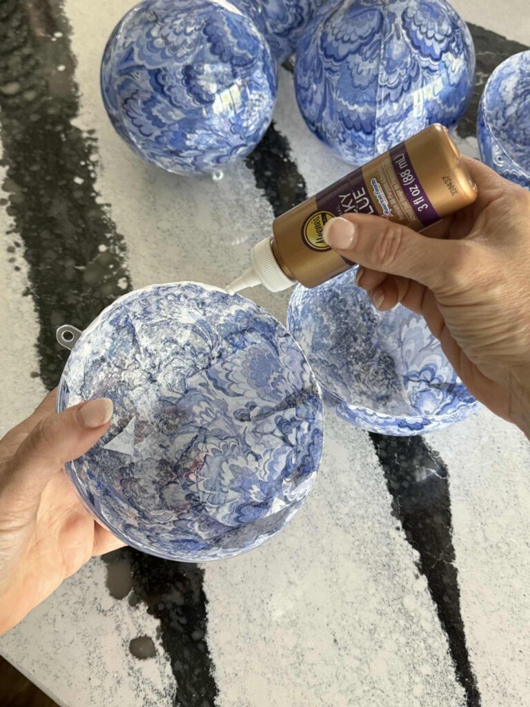 Applying craft glue to the edge of a clear ornament ball.