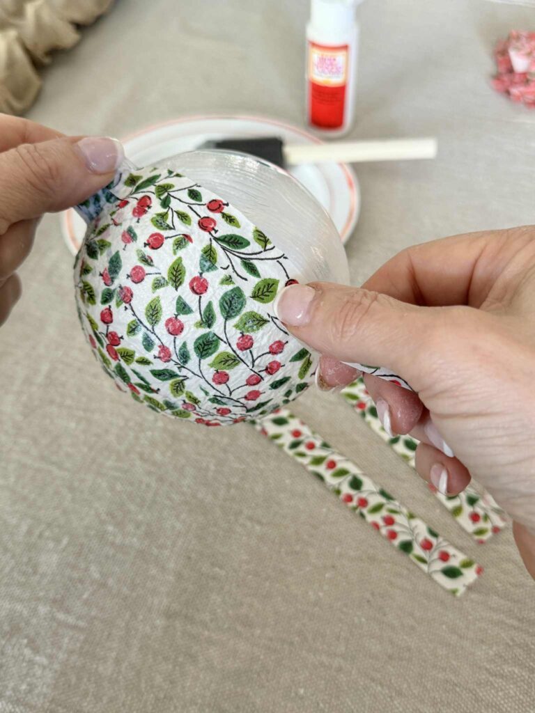 Applying paper napkin strips to a glued ornament ball.