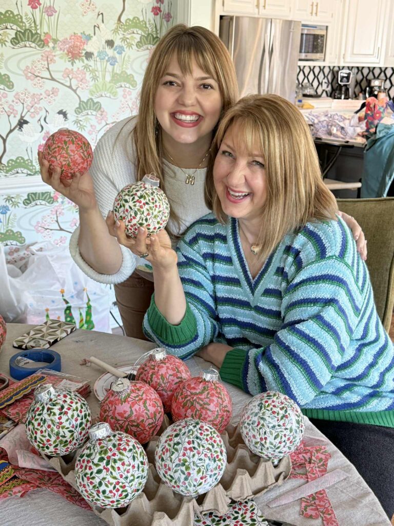 Two women holding decoupage Christmas ornaments.