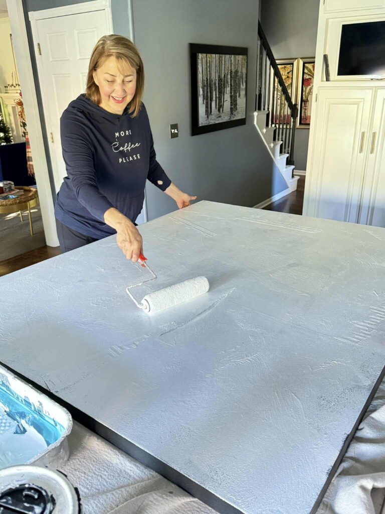 Woman priming the top of an old art canvas.