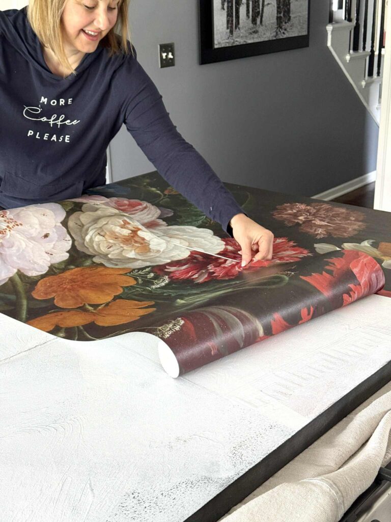 Woman applying wallpaper to an old canvas.