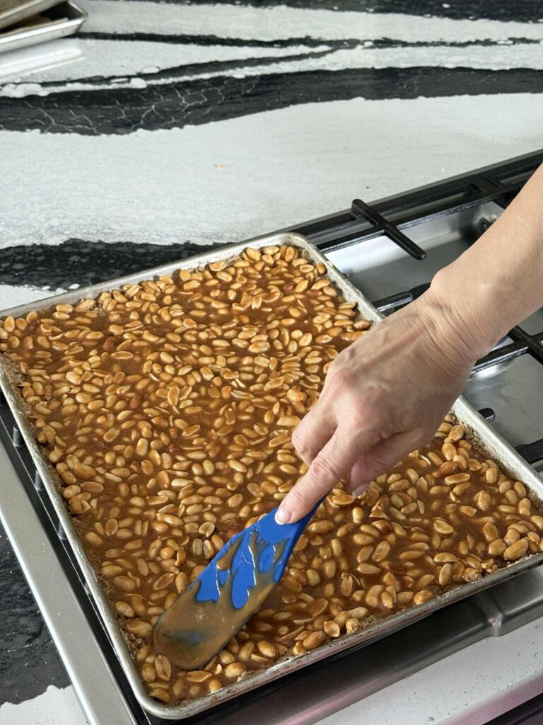 Spreading a caramel peanut mixture on top of a baked crust.