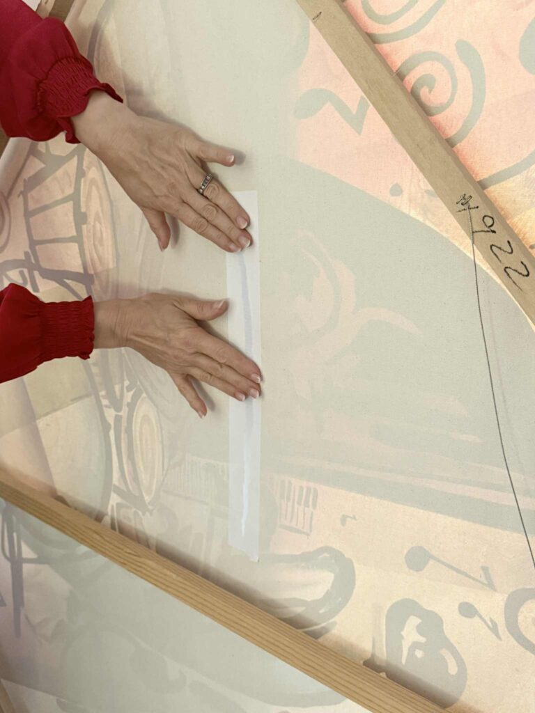 Taping a gash in a canvas art piece.
