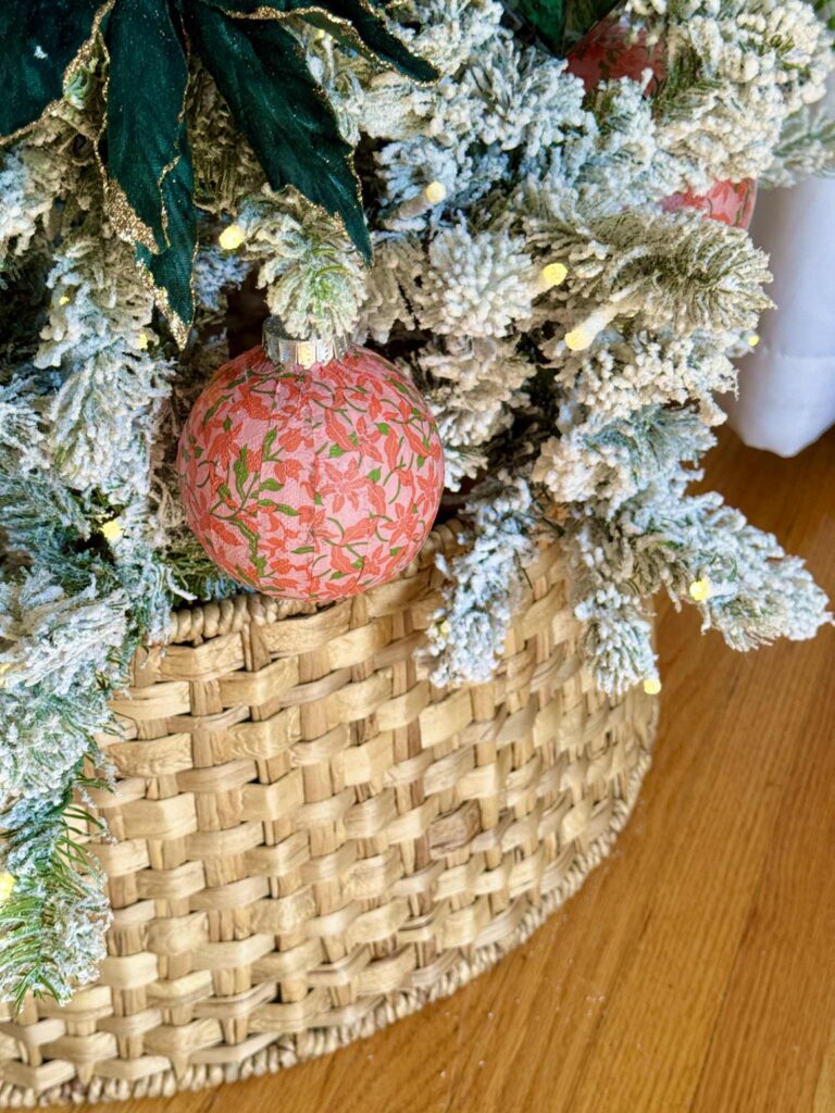 A woven tree collar around the base of a flocked Christmas tree.