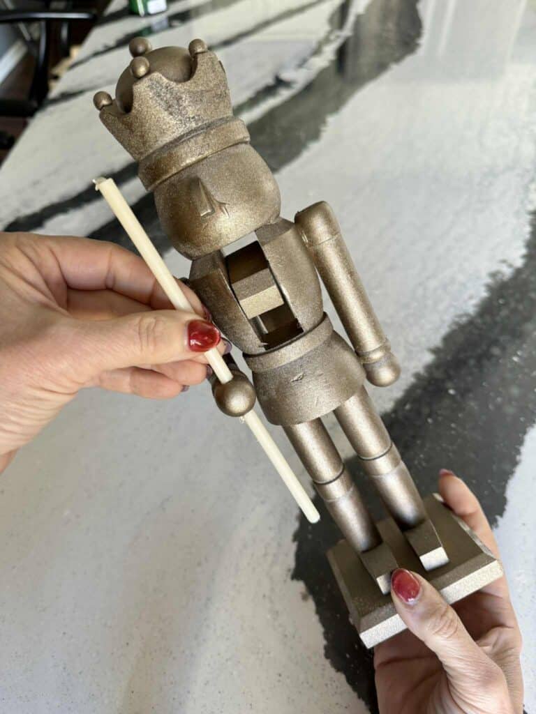 Woman's hand pushing a thin taper candle into a hole in a nutcracker's hand.
