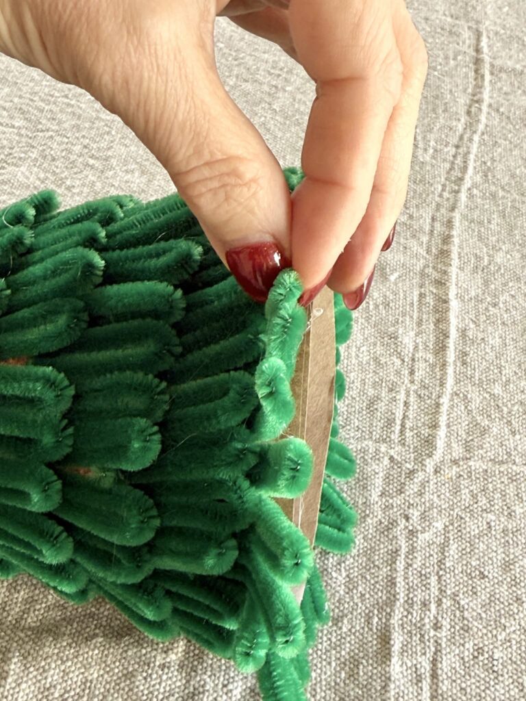 Bending the bottom row of pipe cleaner loops on a diy tabletop Christmas tree.