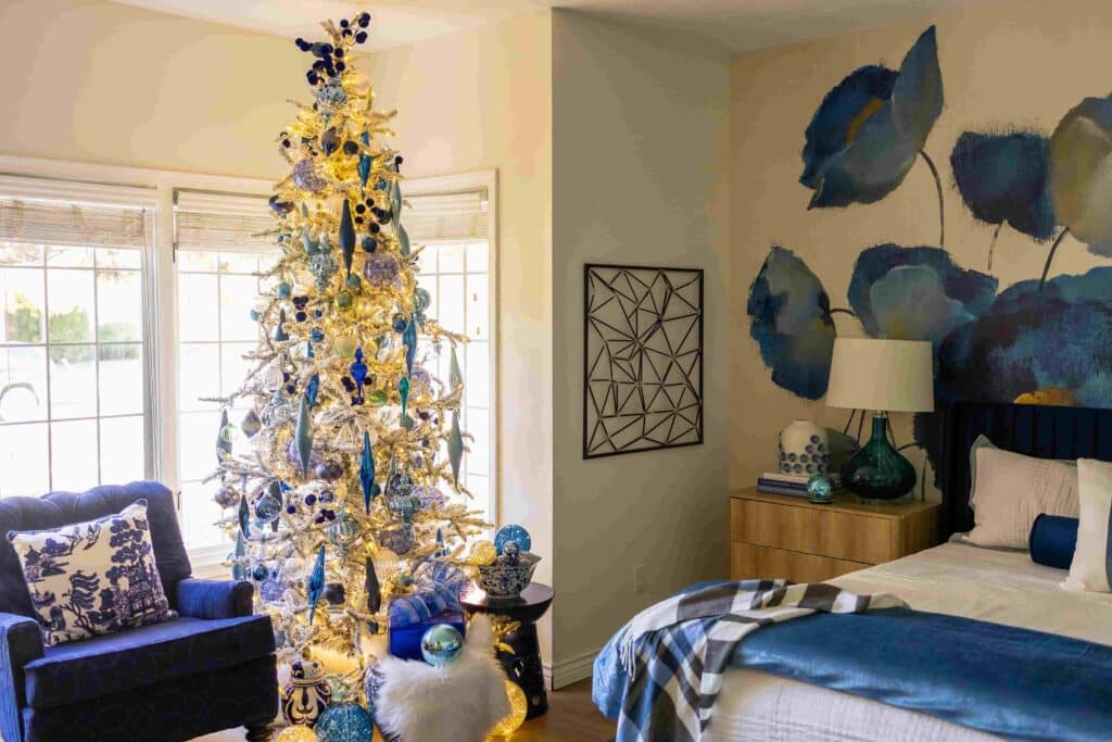 A primary bedroom decorated with a white flocked Christmas tree.