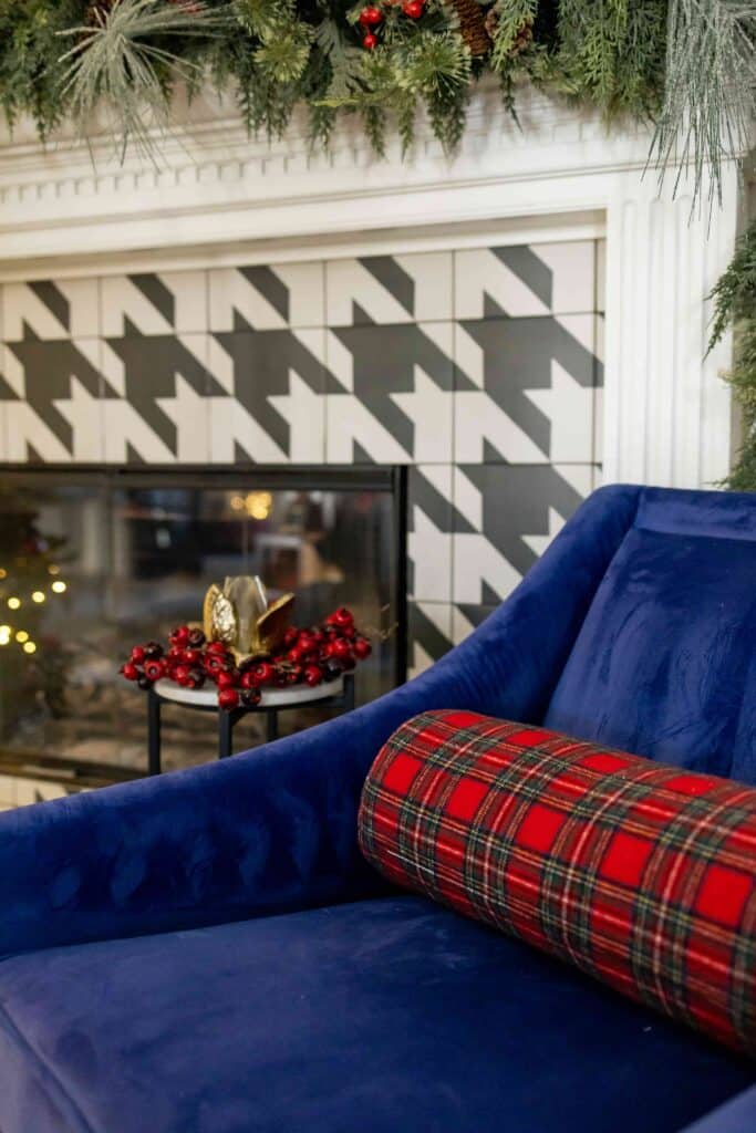 Blue chair with red bolster pillow by Christmas decorated fireplace.