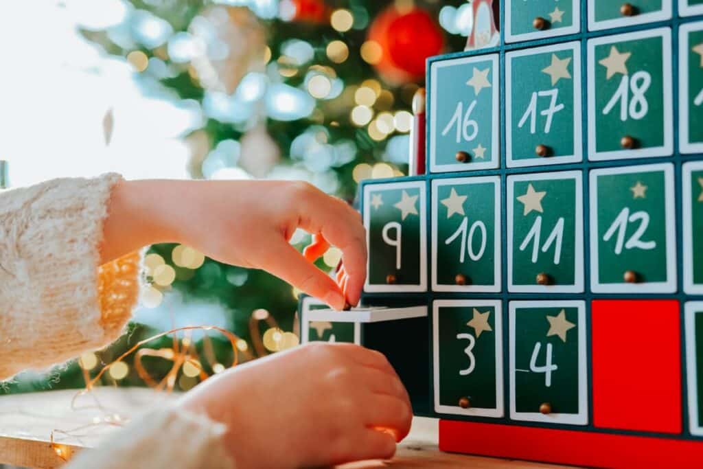 A child's hands reaching for an Advent calendar gift.
