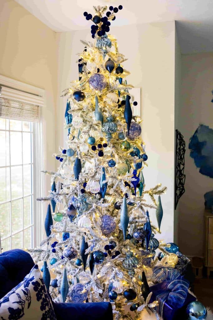 Christmas tree decorating: a flocked Christmas tree decorated with ornaments in shades of blue.