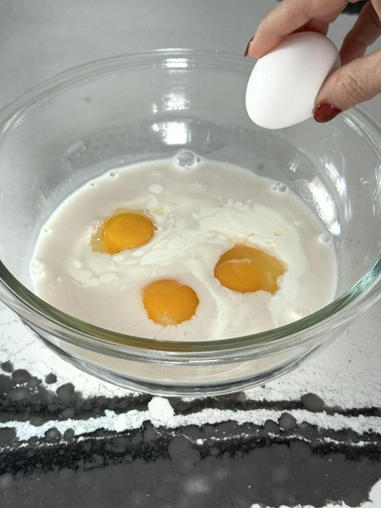 Cracking an egg into a bowl for English muffins French toast.