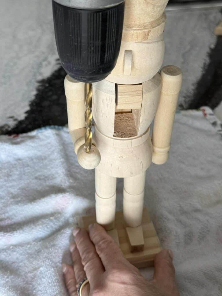 Drilling a hole through a nutcracker's wood hand.