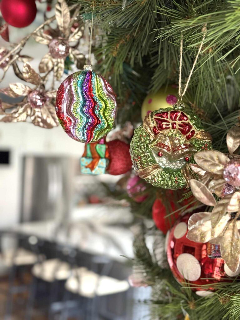 Colorful glass ornaments hanging from a Christmas tree.
