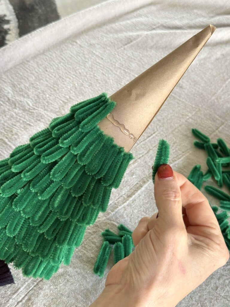 Layering pipe cleaner loops onto paper Christmas tree cone.