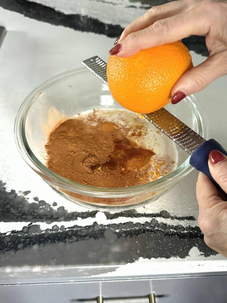 Adding orange zest to custard for English muffins French toast recipe.