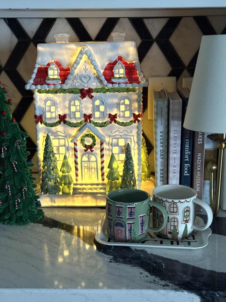 A lighted countertop house decorating a Christmas kitchen.