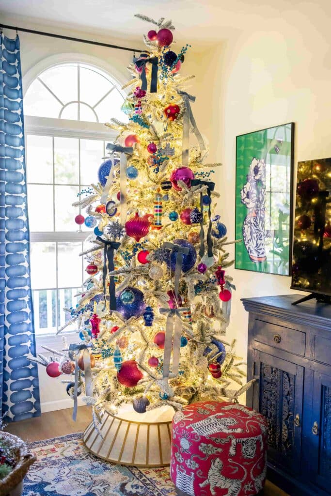 Christmas tree decorating: a flocked Christmas tree with pink and blue ornaments.