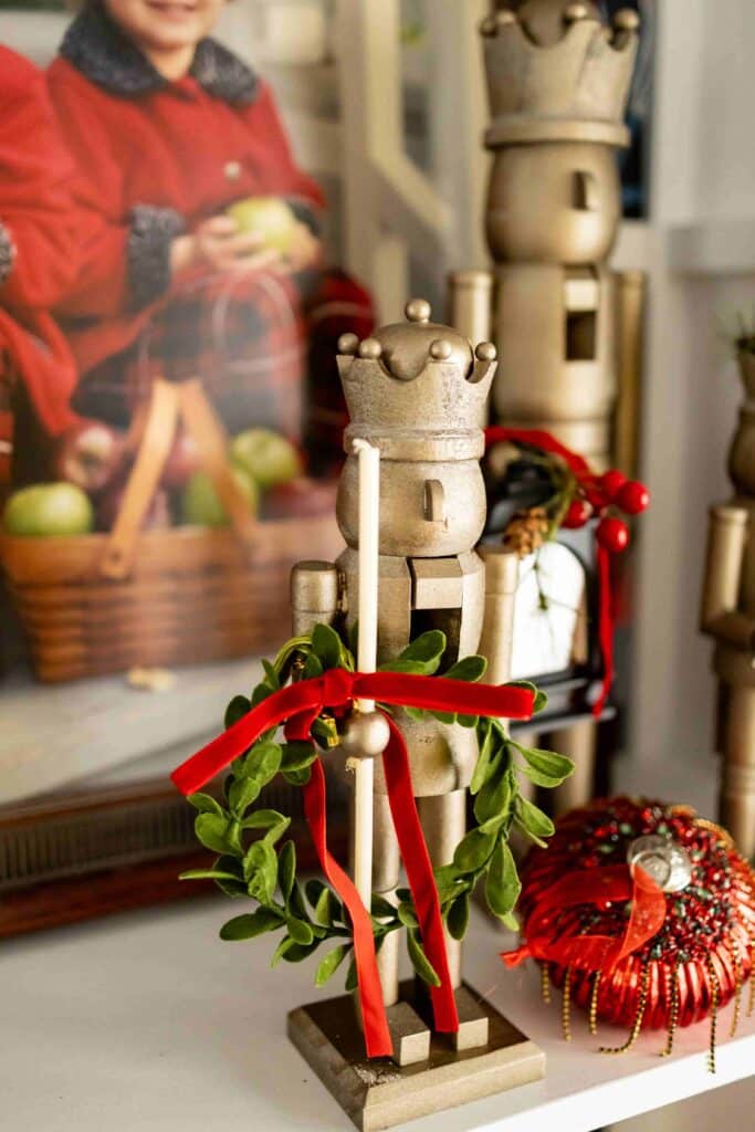 A nutcracker with the decor idea of hanging a small wreath from it's hand.