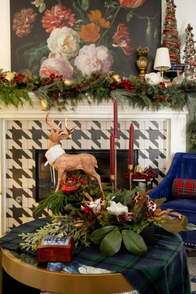 Fireplace with houndstooth patter, greenery, magnolias. burgundy taper candles and copper deer accent for Ralph Lauren Christmas aesthetic.