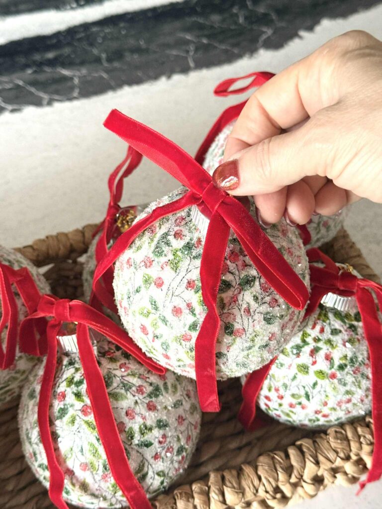 Adding a red velvet bow to decoupage Christmas ornaments.