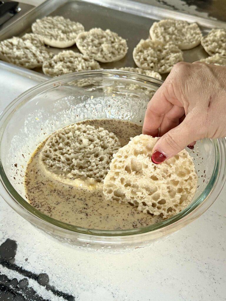 Dunking English muffin halves into French toast custard mixture.