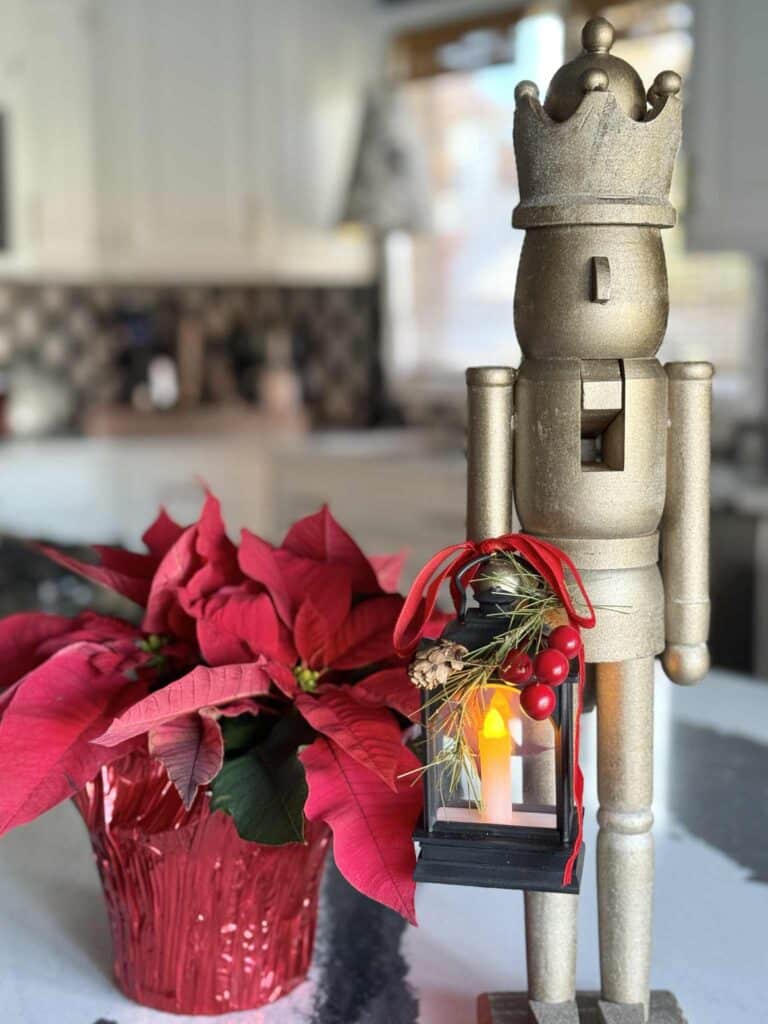 A painted wood nutcracker holding a small lighted lantern decorated for Christmas.
