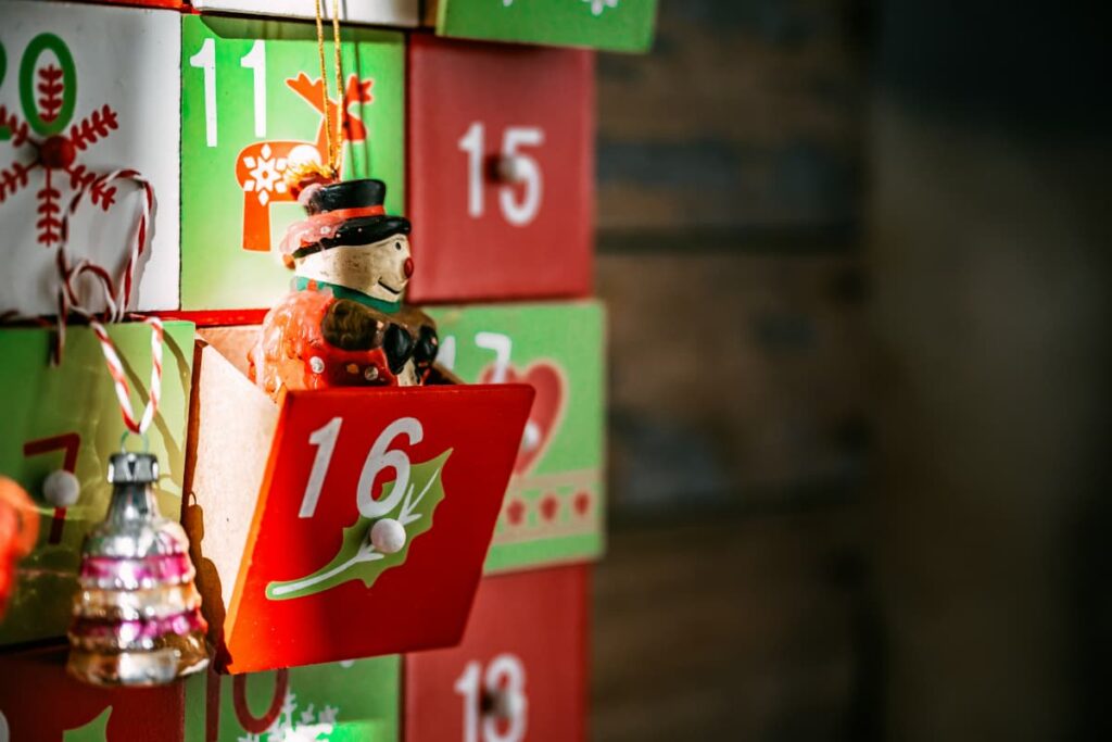 A tiny snowman figure sitting in a drawer of an advent calendar.